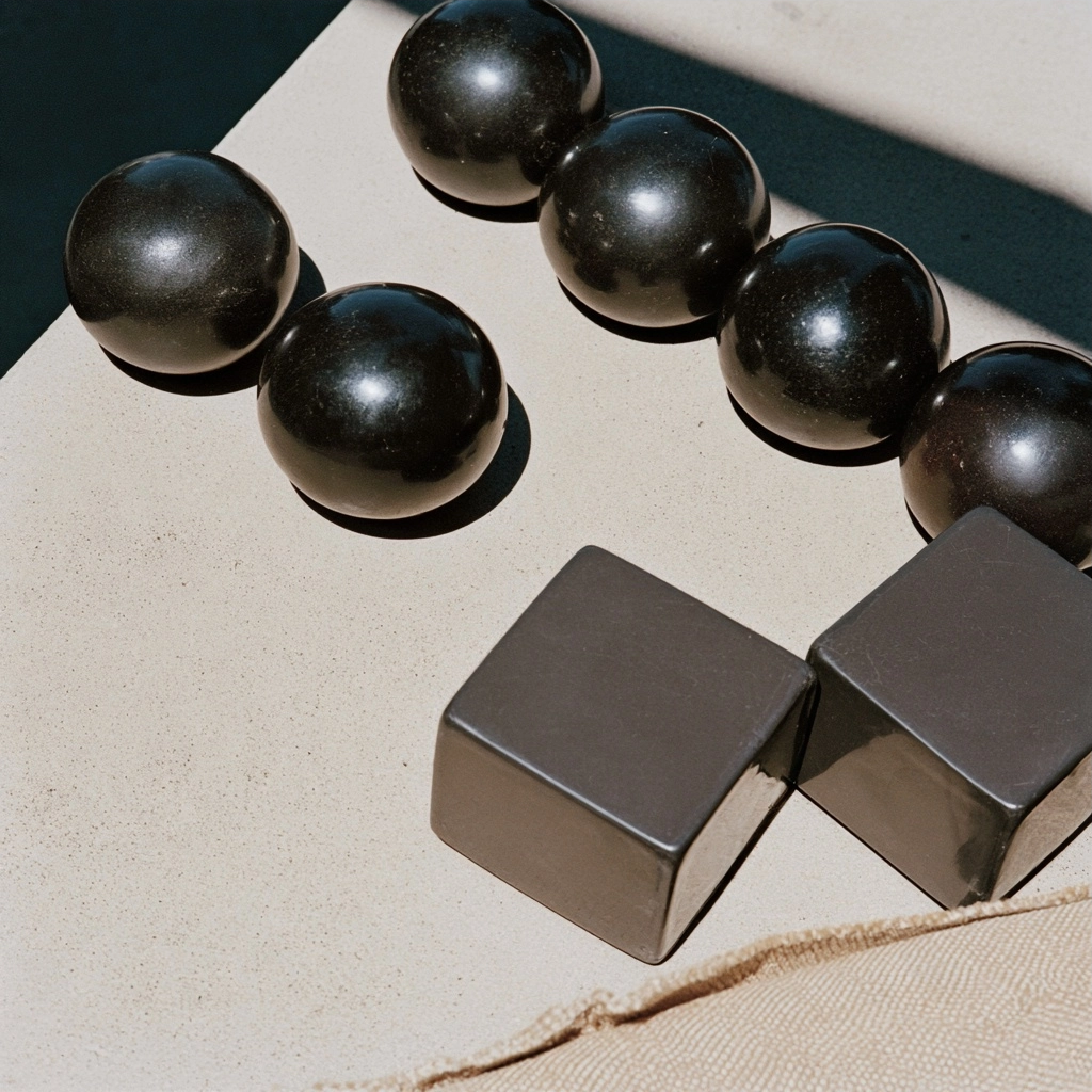 Black geometric spheres and cubes casting shadows on a beige textured surface.