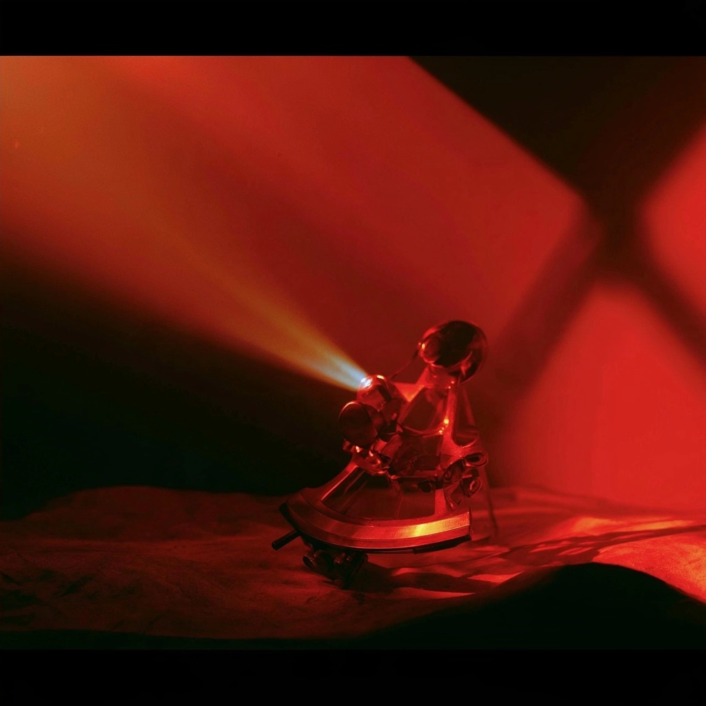 A glowing mechanical device projecting a sharp beam of red light through a dark space.