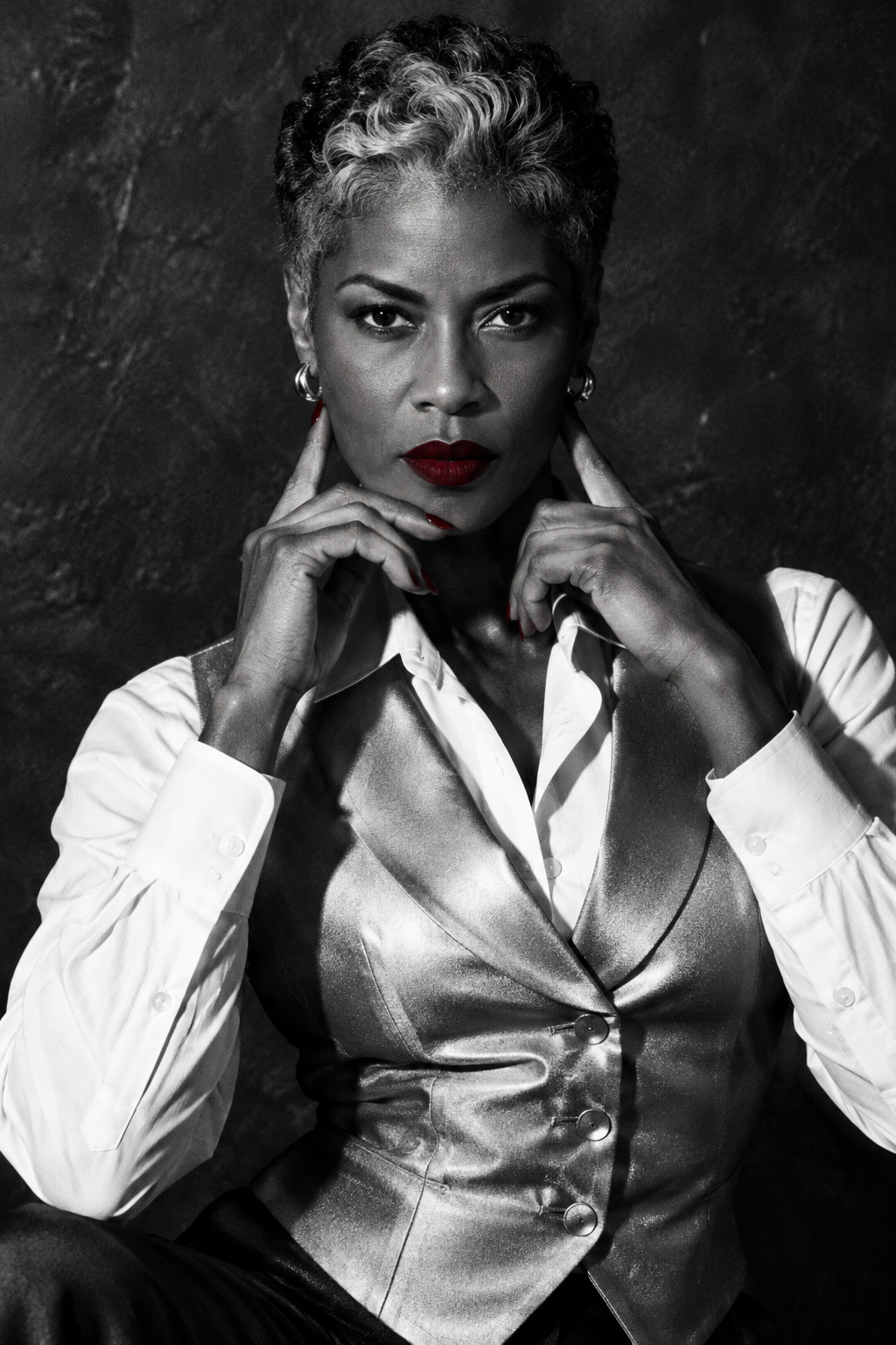 Black and white studio portrait of a woman with short hair posing in a satin vest.
